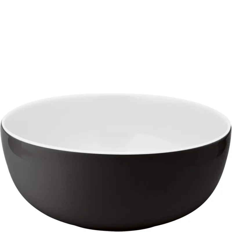 Schlichte, runde Schüssel mit mattem, schwarzem außen und glänzendem, weißem Innen. Die Schüssel hat einen breiten Rand und eine sanft geschwungene Form, die einen modernen Look vermittelt. Sie eignet sich gut für die Zubereitung und Präsentation von Speisen.