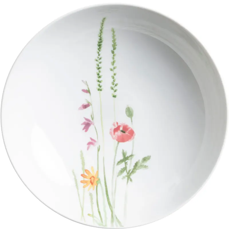Ein rundes, flaches Geschirr, das in Weiß gehalten ist. Auf der Innenseite des Tellers sind zarte, farbige Aquarell-Muster von verschiedenen Blumen, darunter eine Mohnblume, farbige Blüten und grünes Gras. Der Teller strahlt eine frische, natürliche Ästhetik aus und vermittelt einen rustikalen, botanischen Stil.